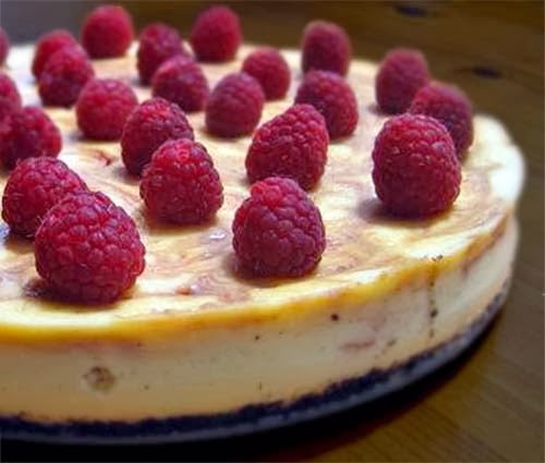 White chocolate cheesecake with raspberry swirls topped with fresh raspberries.