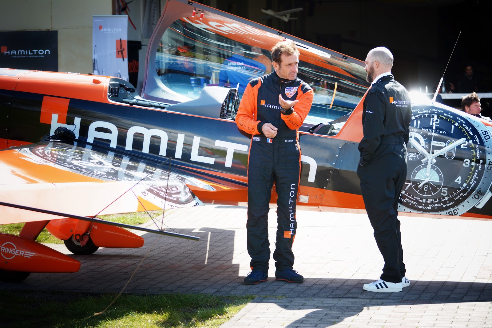 Nicolas Ivanov mit Jens Mahnke vor seinem Hamilton Kunstflugzeug vor einem Hangar - Zwei personen stehen vor einem Flugzeug und diskutieren