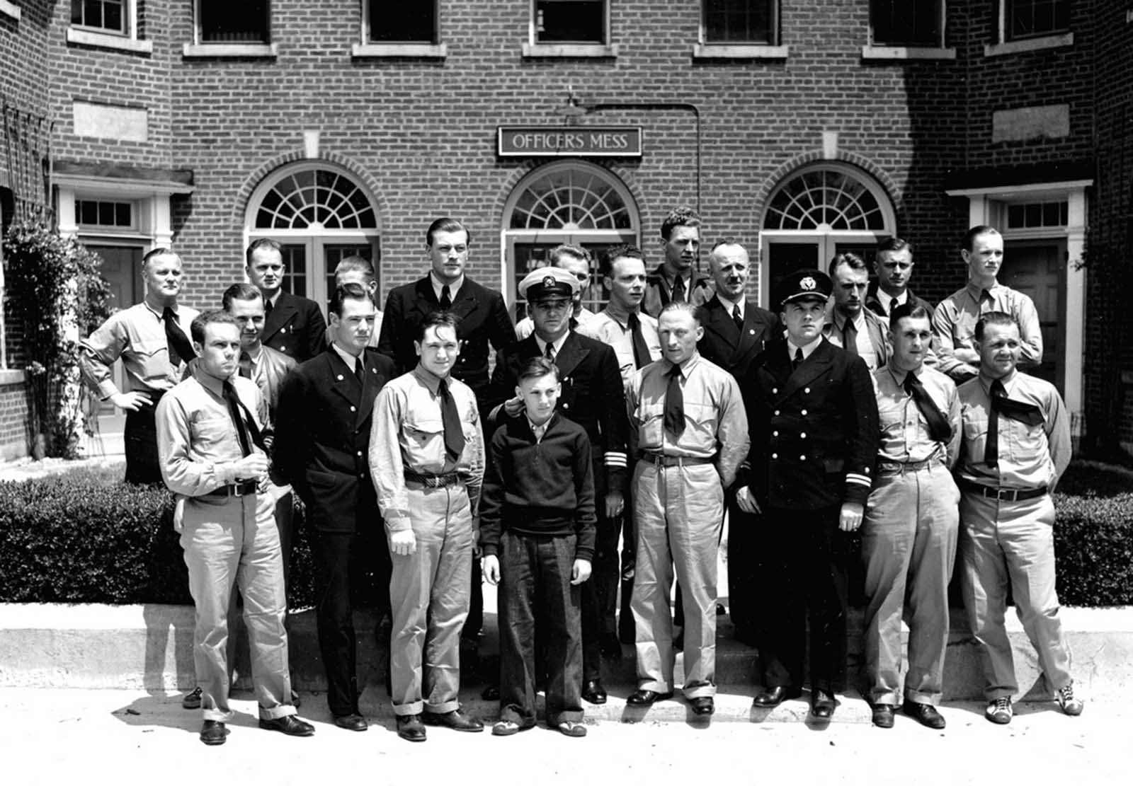 Surviving members of the crew aboard the ill-fated German zeppelin Hindenburg are photographed at the Naval Air station in Lakehurst, New Jersey, on May 7, 1937. Rudolph Sauter, chief engineer, is at center wearing white cap; behind him is Heinrich Kubis, a steward; Heinrich Bauer, watch officer, is third from right wearing black cap; and 13-year-old Werner Franz, cabin boy, is center front row. Several members of the airship's crew are wearing U.S. Marine summer clothing furnished them to replace clothing burned from many of their bodies as they escaped from the flaming dirigible.