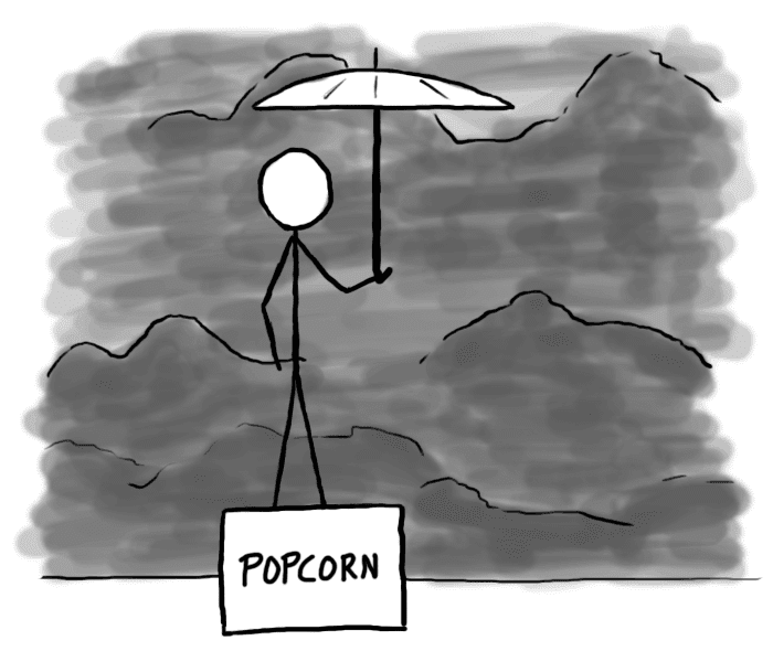 Sateenvarjoa pitävä henkilö popcorn-laatikon päällä, taustalla synkkiä pilviä.