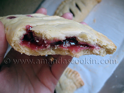 A close up photo of a half eaten cherry hand pie.