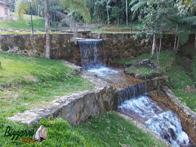 Execução do paredão de pedra, com pedras brutas, na construção do lago com a cascata de pedra com a ponte de madeira. Muro de pedra em Piracaia-SP.