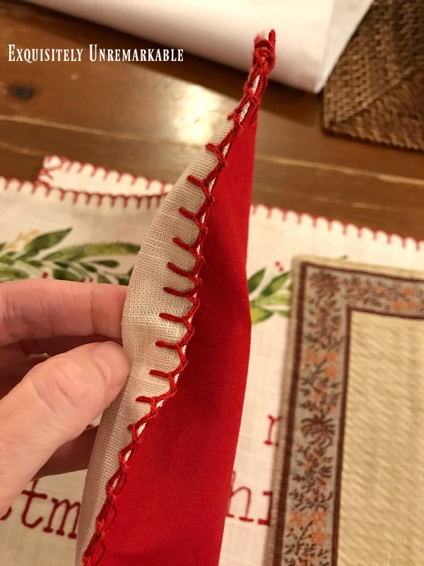Hand holding a pillow to point out decorative stitching on placemat