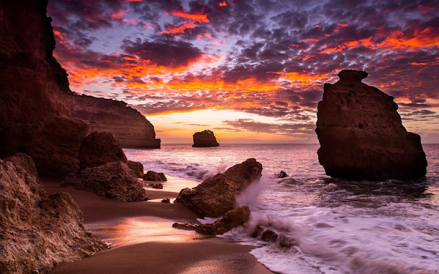 صورة للطبيعية أثناء غروب الشمس على شاطئ البحر بسماء ملبدة بالغيوم