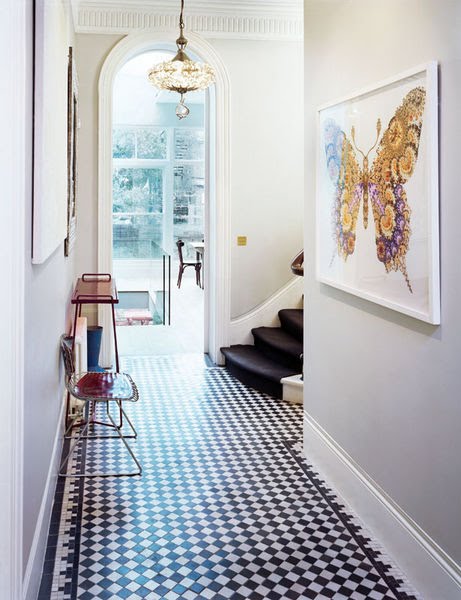 Foyer with black and white checkered floor, dentil moulding, a crystal pendant light, and a butterfly painting
