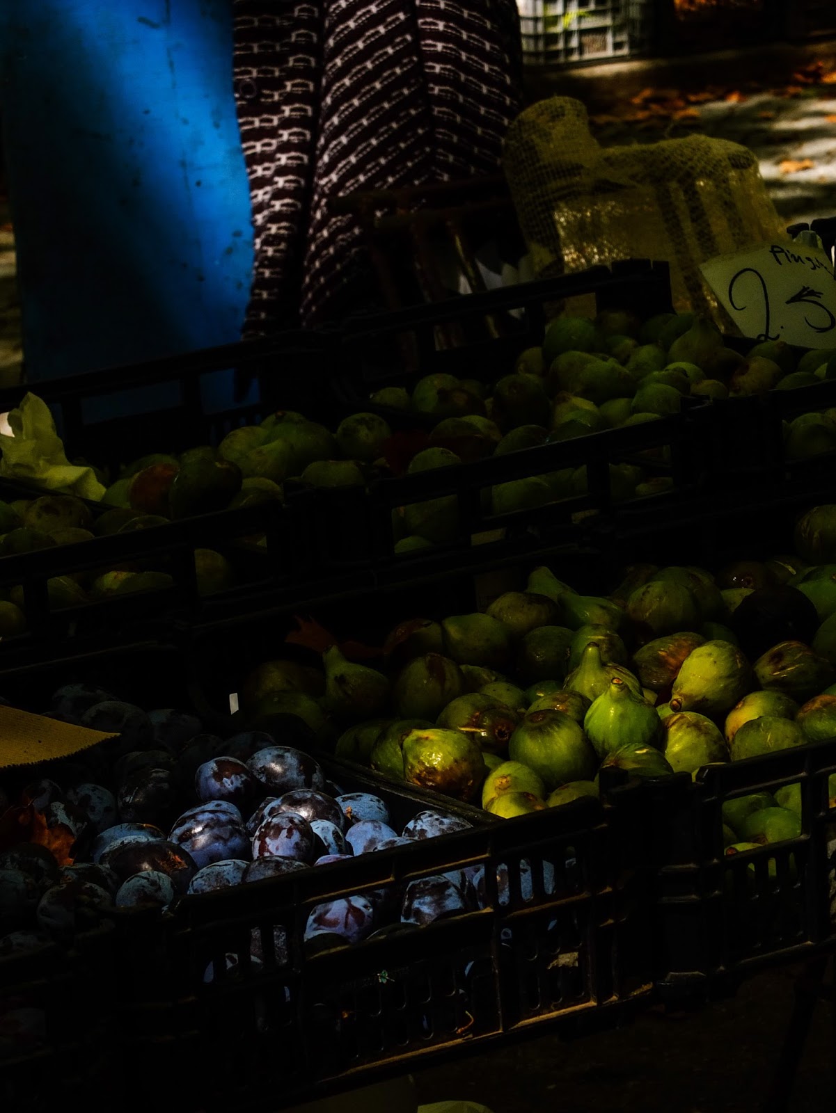 Purple and green figs displayed in crates in sunlight at a market in Porto, Portugal.