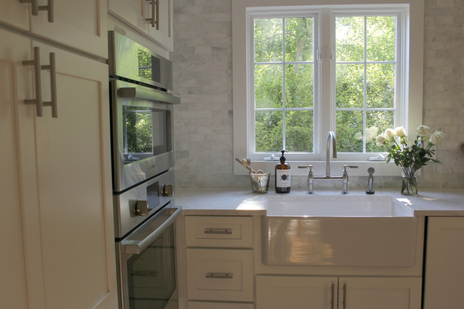 Modern farmhouse kitchen with apron front farm sink and marble subway tile by Hello Lovely Studio