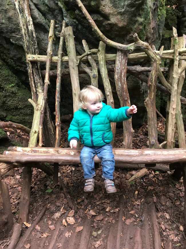 toddler sat on a bench made from sticks