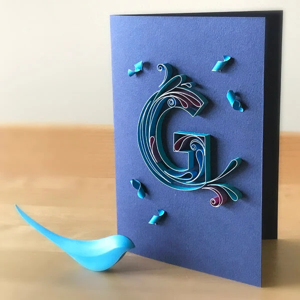 Quilled uppercase letter G filled with quilled scrolls on card front