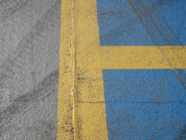 Blue parking spaces outlined with yellow with grey route for moving cars.