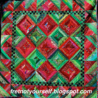 String quilt of green and red fabric strings.