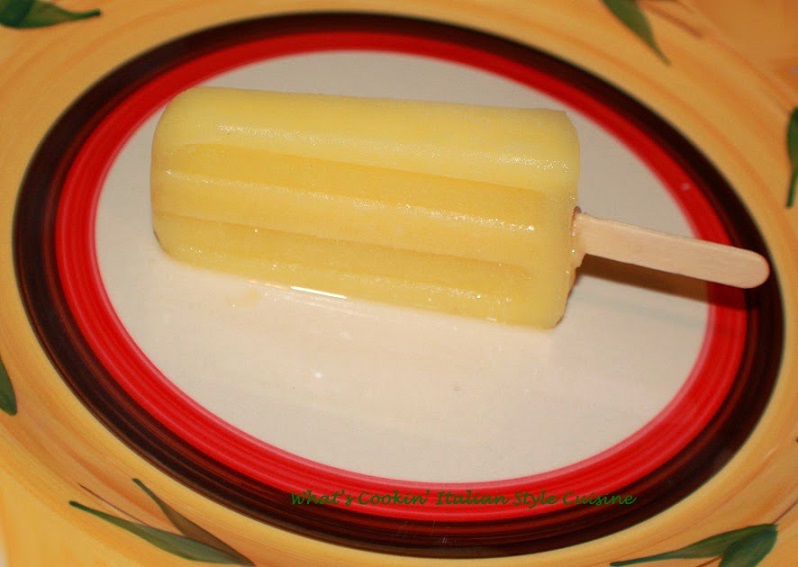 This is an adult popsicle with a pina colado pineapple base in it frozen on a stick in a Mexican style plate.