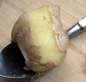 peeling fresh ginger with a spoon