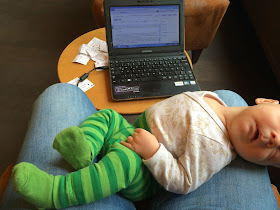 Baby liegt beim Schreiben am Laptop