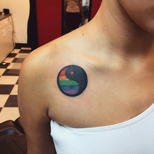 Um sublocar e minimalista Yin Yang tatuagem. Criado em tinta colorida, a tatuagem mostra um todo lado preto em contraste com um colorido arco-íris do lado do elemento.