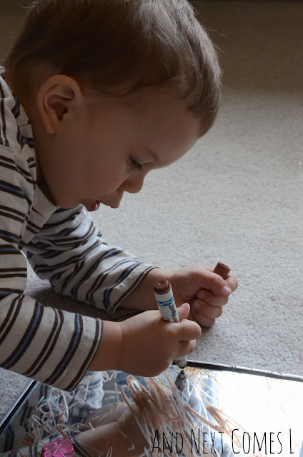 Young child drawing on mirrors with window markers