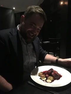Bren smiling over a plate of Wallaby steaks at Pure South restaurant