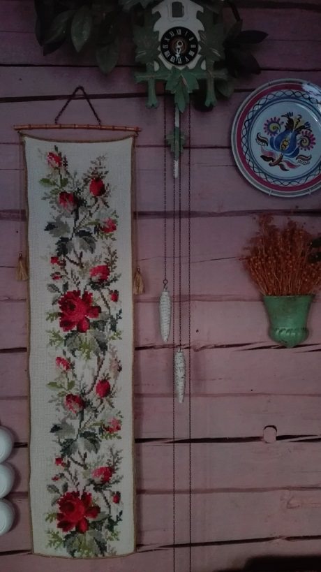 Ruokasalin seinää koristaa mm. kaunis ristipistotyö. ruusukuvioinen käsityö vanha seinäkoriste