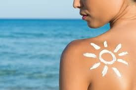 A women at a beach applying sunscreen 