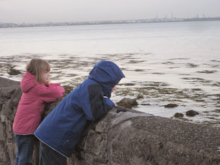 Children looking over a low wall at the sea