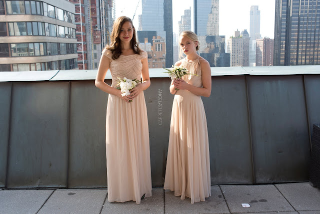Two junior bridesmaids show off part of the view from the roof top at the NY Athletic Club wedding.