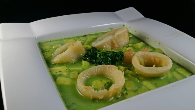 Una sopa de kale de color verde con calamares de adorno