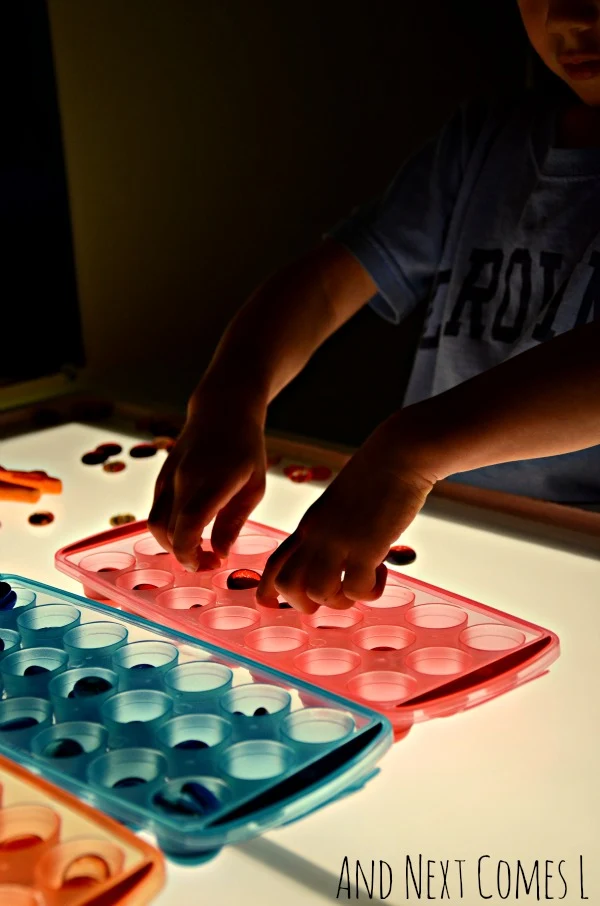 Light table activity using dollar store ice cube trays for fine motor practice from And Next Comes L