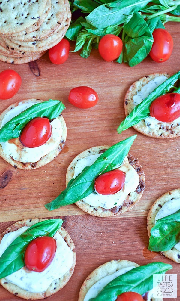 Caprese Crackers | by Life Tastes Good are gluten free, bite sized morsels of deliciousness! Topped with a garlic and herb cheese spread, fresh basil leaves, tomatoes, and a drizzle of balsamic dressing, these appetizer bites are tasty any time of day, and especially perfect for a party, as they are easy to make and so enjoyable to eat!