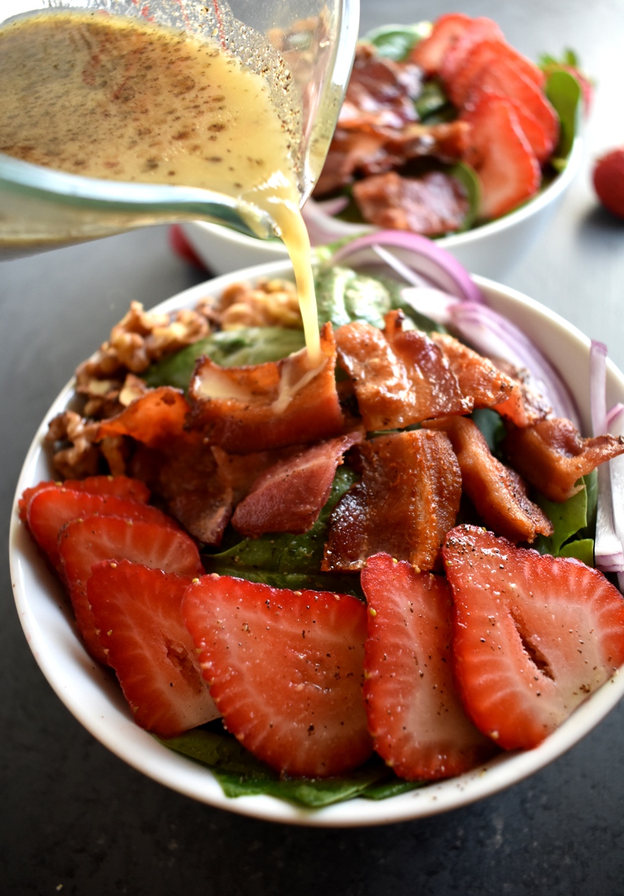 Strawberry Spinach Salad with Warm Bacon Vinaigrette is the perfect salad with red onions, strawberries, crispy bacon, toasted nuts and a warm bacon dressing! www.nutritionistreviews.com
