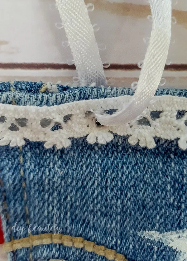 thread ribbon through punched holes in denim pocket