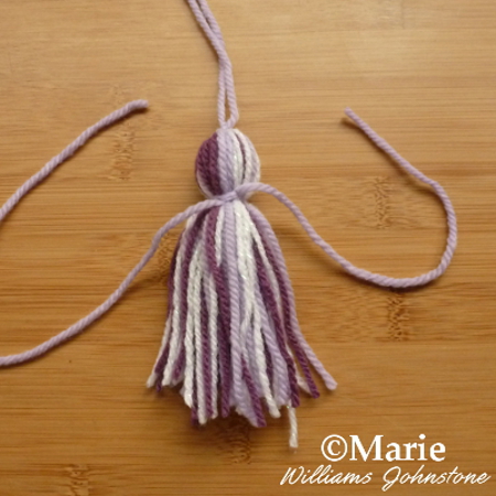 Tying around the pieces of gathered yarn to make a simple  DIY yarn wool tassel