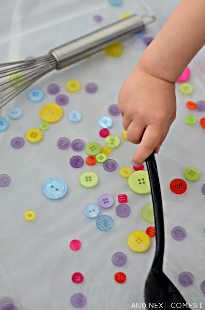 Child playing with buttons in a water sensory bin
