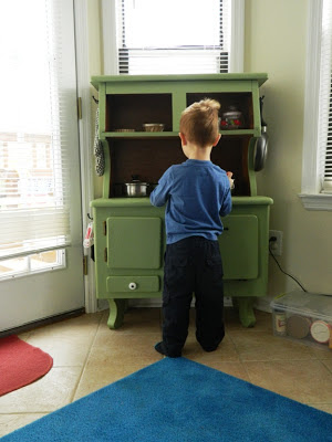Close-up of green armoire and young boy standing in front of it