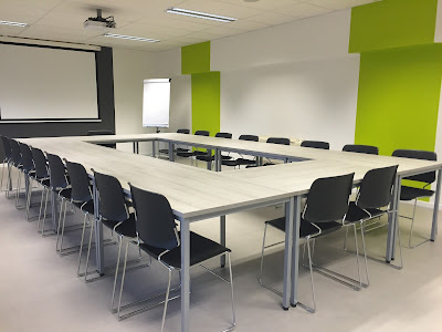 lecture chairs positioned around tables configured in a large rectangular shape