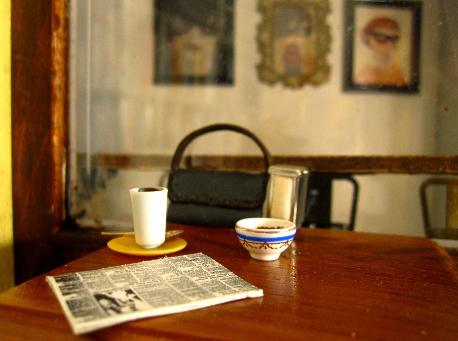 Modern dolls' house miniature cafe table with a newspaper, a latte, a sugar bowl and a handbag on it.