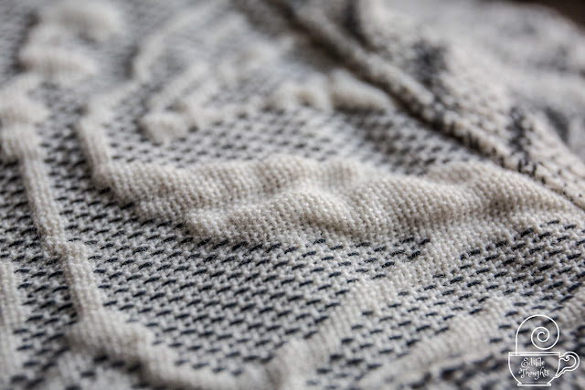 Close-up image of a gray wrap's black and ecru threads. The gauzy cloud-like texture of puffiness that's signature of the Arcadia line of woven wraps by Bijou is apparent.