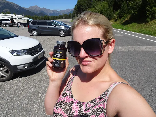 woman with bottle of focus tablets in mountains