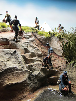 Diorama of 19th-century soldiers fetching water from a stream.