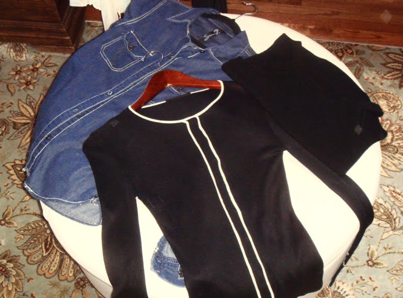 Solid and transitional tops to pack. Tops laid out on ottoman. A jean shirt, a super lightweight black cardigan,and a black sleeveless top.
