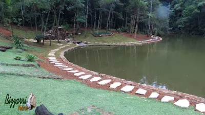 Execução do caminho com pedras em volta do lago com o muro de pedra em volta do lago, sendo caminho com pedra cacão de São Tomé com junta de grama.