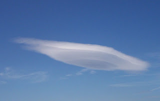 A strangely disc-shaped cloud gives the appearance of a UFO in the sky.