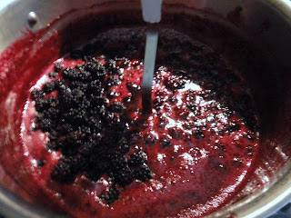 Blackberries being mashed in pot.