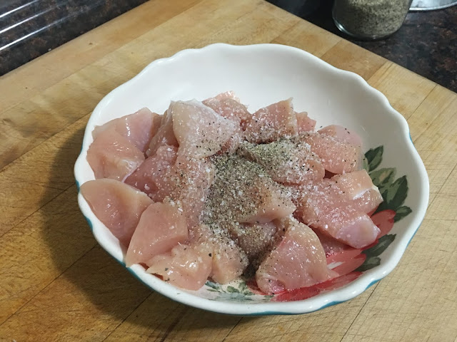 The uncooked chicken, in a bowl, with salt and pepper on it.  