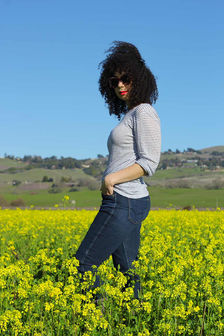 natural hair style with girl standing in a yellow mustard field 
