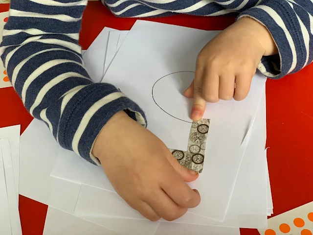 A toddler Sticking washi tape on the straight line parts of the number 5
