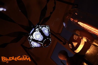Night photo of glowing vintage-style Halloween lantern (The Horrid Decor #2 Pus & Bruis on Ghost Skin) by Bindlegrim hanging over a authentic vintage paper Jack O'Lantern pumpkin