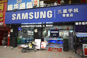 store with large Samsung sign displaying Nokia and Apple products