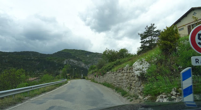 Keine ausgebaute Landstraße mehr, ein Feldweg mit Asphalt, rechts ein Verkehrsschild, Berge, Mauer