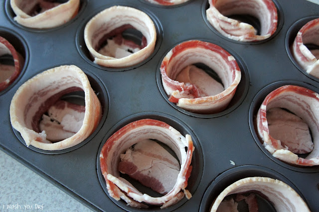 A muffin tin with bacon lining each muffin space.