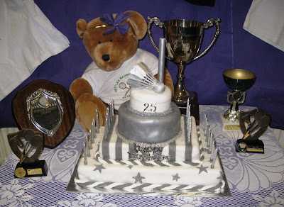 Bear mascot, trophies and 25th anniversary cake featuring silver shuttlecocks